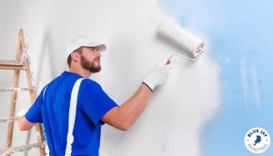 Man on ladder rolling on a coat of white paint