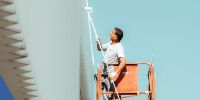 Man using a paint roller on the front of a warehouse