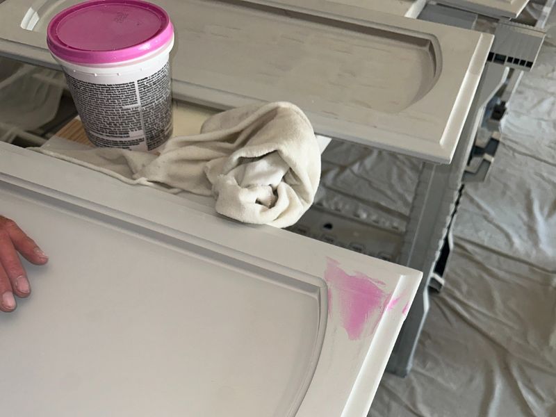 Applying putty to the uneven surfaces of wooden cabinets before painting them